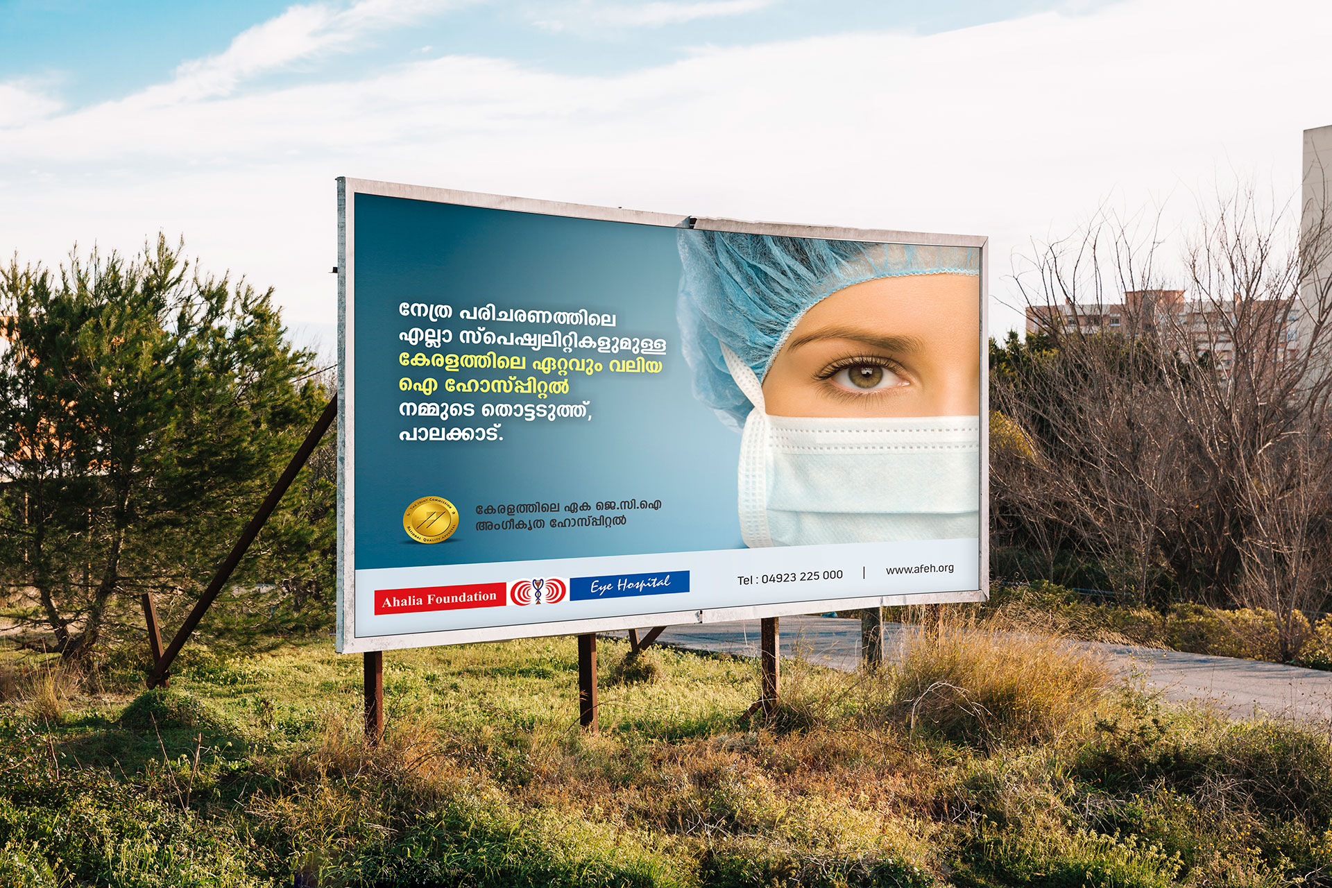 A bill board on landscape displaying the Ahaliya Eye Foundation Hospital design consists of a surgeon with mask
